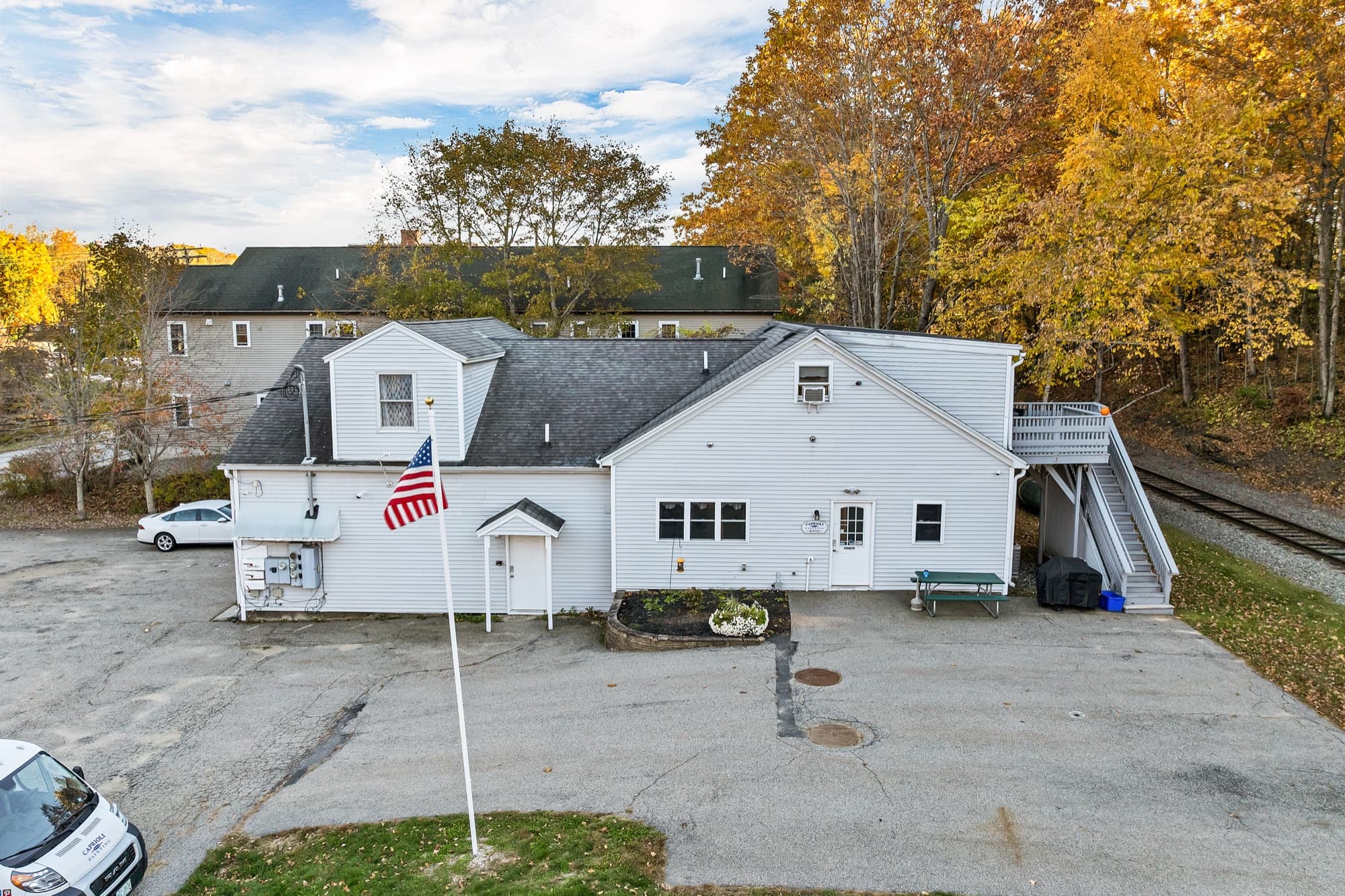The office entry on the street side, with the flagpole, the front walk, and the exterior stair to the apartments at the right