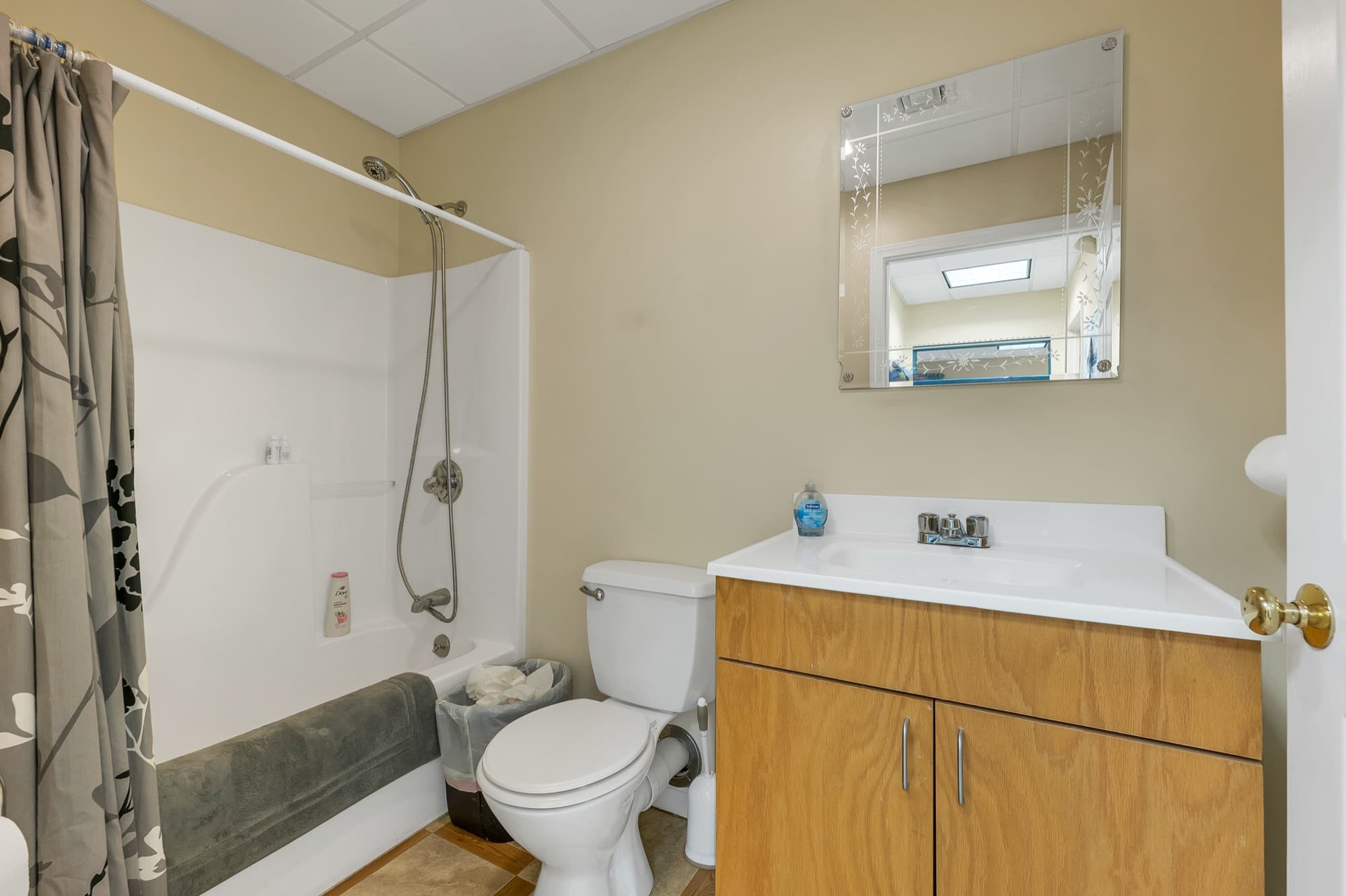 The office bath with a tub and shower, a vanity, and a mirror