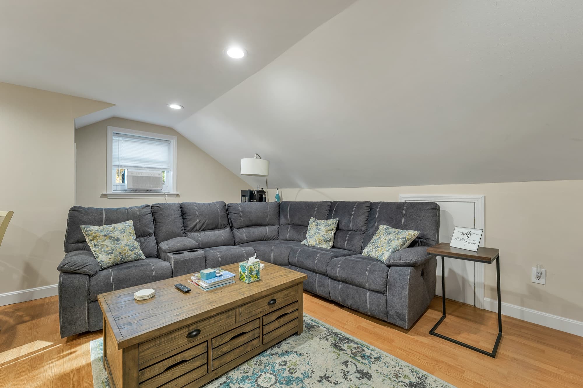 The 2-bedroom apartment's living room with a sectional under the sloped ceiling and a trunk coffee table