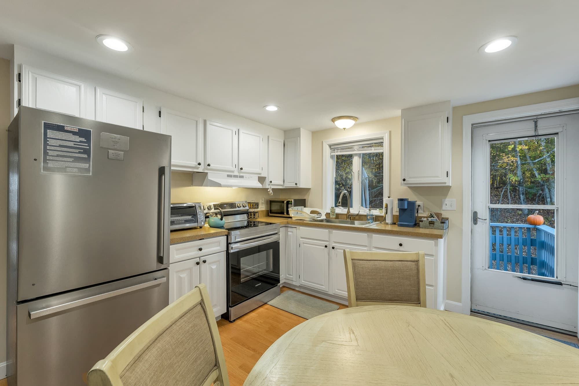 The 2-bedroom apartment's kitchen with white cabinets, a stainless refrigerator and range, and the door to the deck