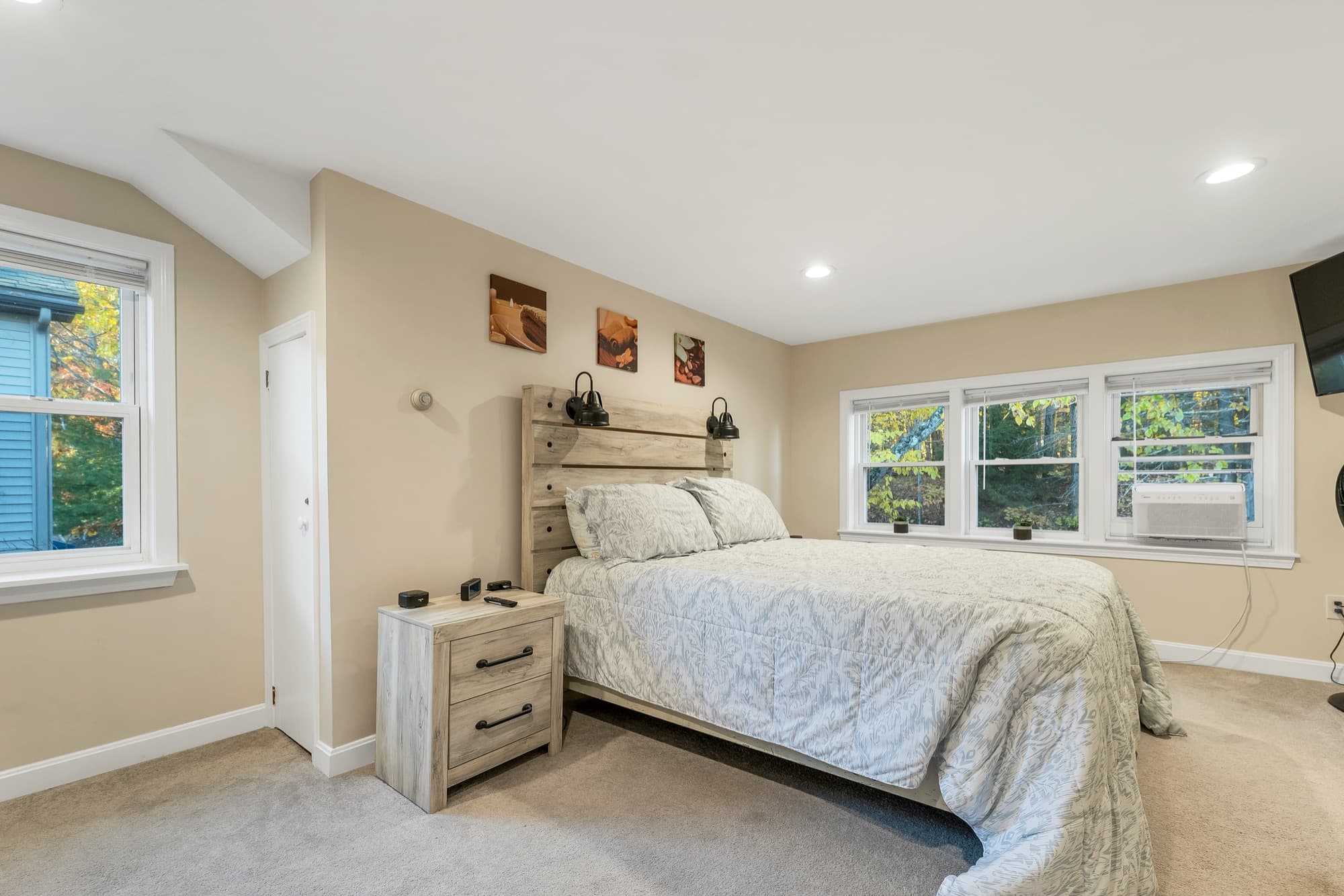 The 2-bedroom apartment's primary bedroom with 3 windows and a nightstand