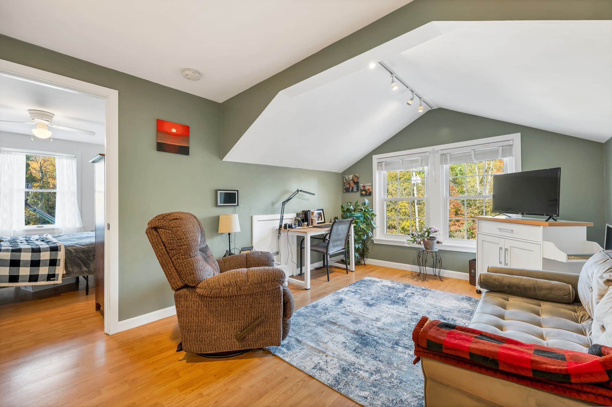 The 1-bedroom apartment's living room with a recliner, a desk, and the sloped ceiling
